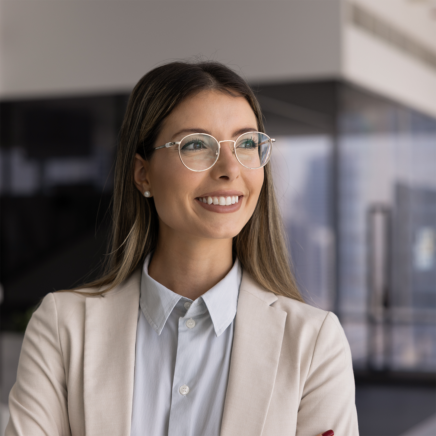 Woman wearing glasses and a beige blazer in an office setting